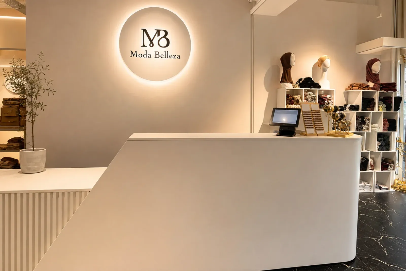 Beleuchtetes rundes MB Moda Belleza Signet über dem Verkaufstresen.