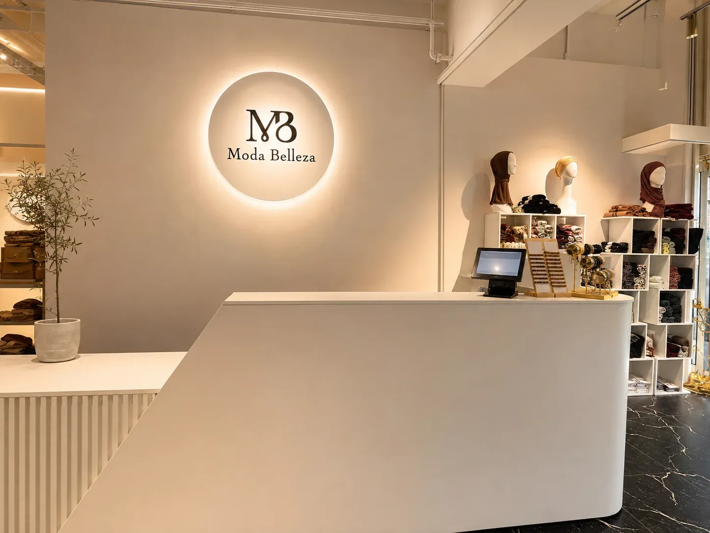 Beleuchtetes rundes MB Moda Belleza Signet über dem Verkaufstresen, daneben ein Regal mit Kopftüchern.